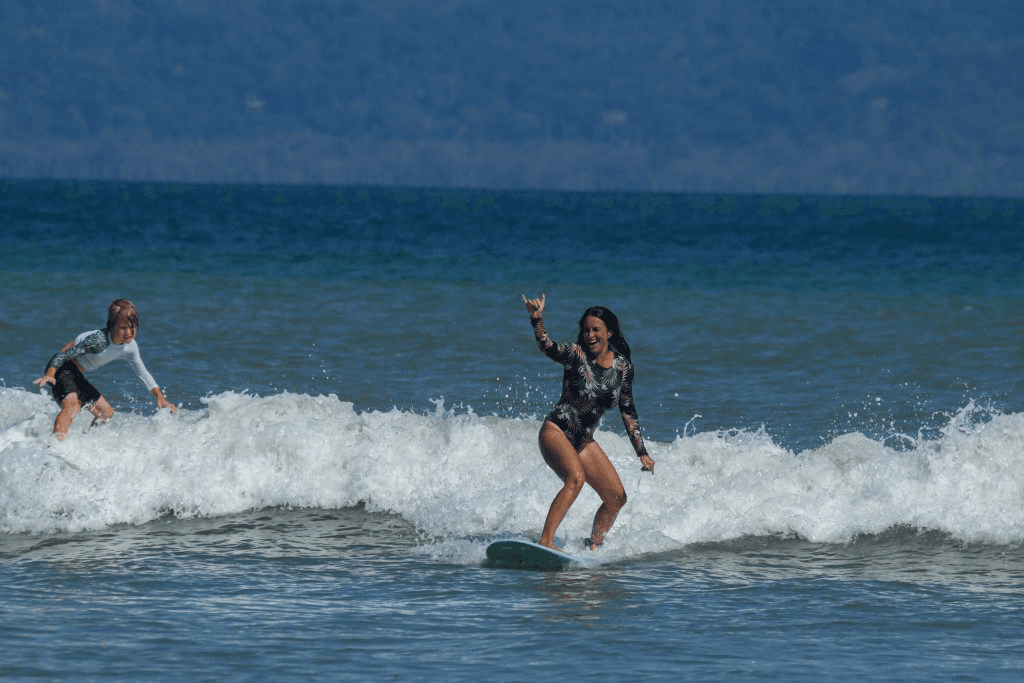 Woman surfing with son at Cabo Matapalo